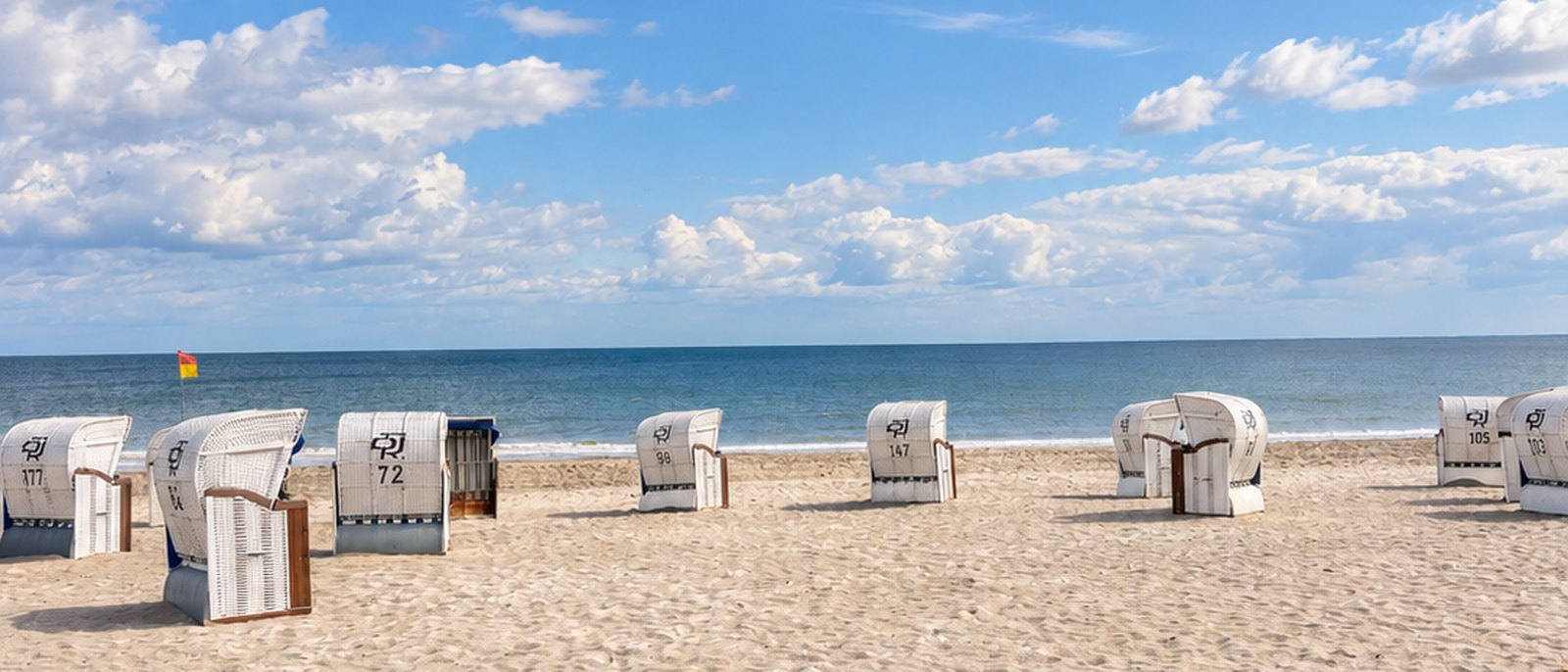 Der Strand von Dahme mit weißen Strandkörben, Dünengras und blauem Himmel über der Ostsee